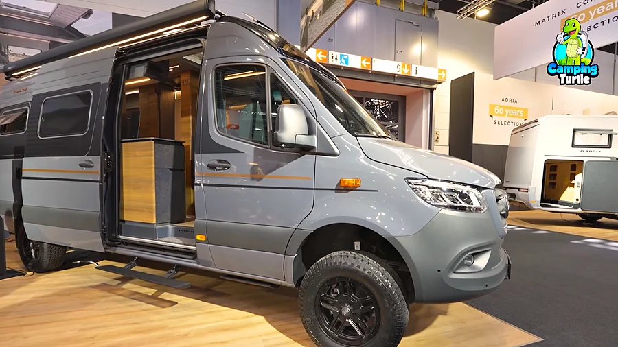 Adria Supertwin 700 SGX schräg von vorn mit offener Schiebetür, ausgefahrener elektrischer Trittstufe und grobstolligen Offroad-Reifen