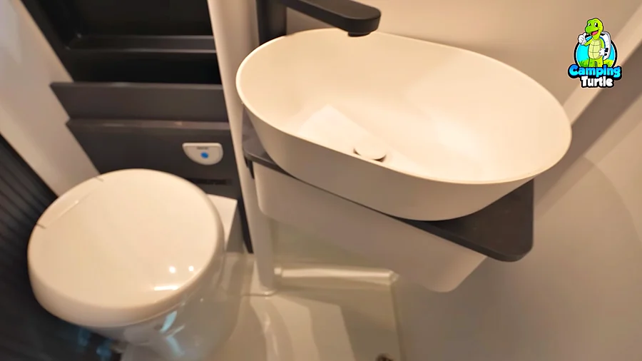 Schwenkbad mit Toilette, weißem Waschbecken auf schwarzer Konsole und Duschwanne mit Ablauf im Boden
