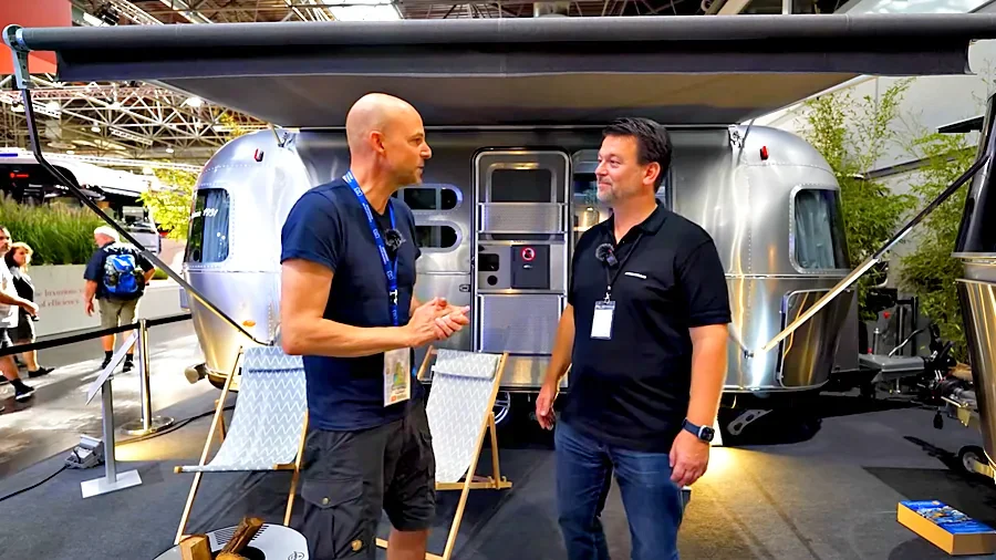 Thomas Sauermann und Armin Heun im Gespräch vor dem Airstream 534 mit ausgefahrener Markise auf dem Messestand