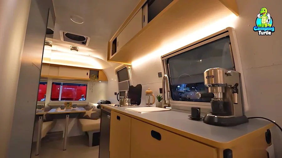 Küchenzeile mit Spüle und Kochfeld, im Hintergrund die Sitzgruppe im Bug des Airstream World Traveler 22