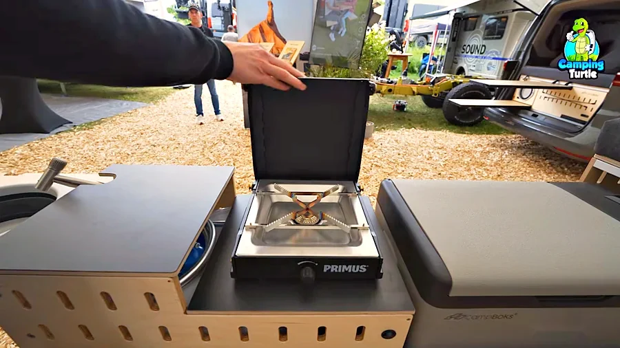 Ausgezogene Küchenzeile der CampBoks Pro 2.0 mit Primus-Gaskocher, Spülbecken und Kompressorkühlbox