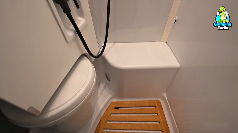 Bad mit Toilette, Sitz in der Dusche und Holzrost auf dem Boden