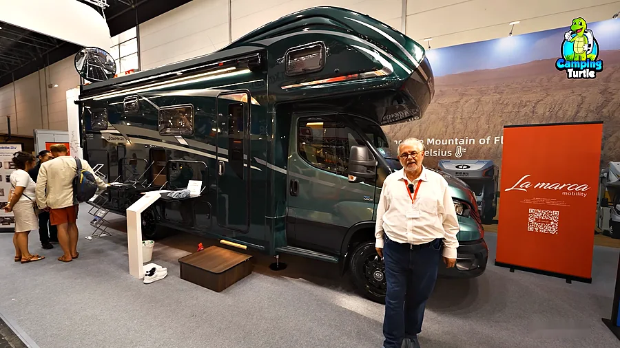 Karl Schlössl steht vor dem dunkelgrünen Deddle RV Carbonic Liner 78 auf dem Caravan Salon 2024.