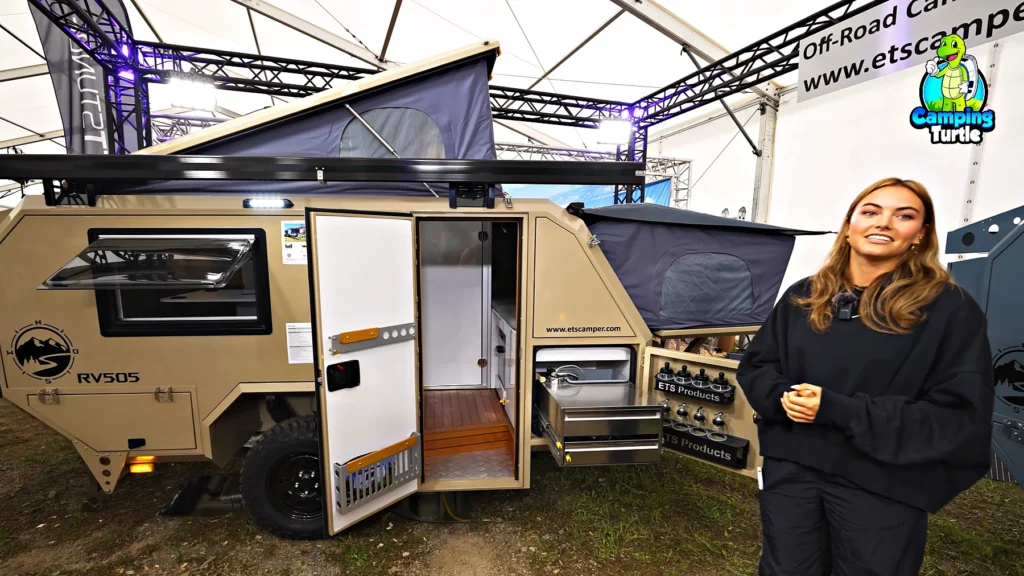 Jil Ruckenstuhl steht vor dem sandfarbenen ETS Camper RV505 mit offener Tür und ausgezogener Küche