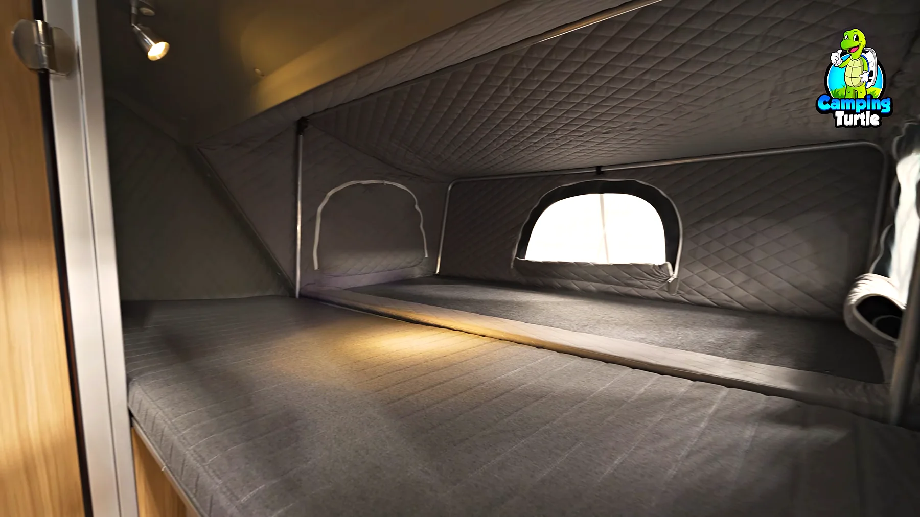 Blick auf das Einzelbett und dahinter das Bett in der ausgeklappten Front mit gesteppten Wänden und Zeltfenster
