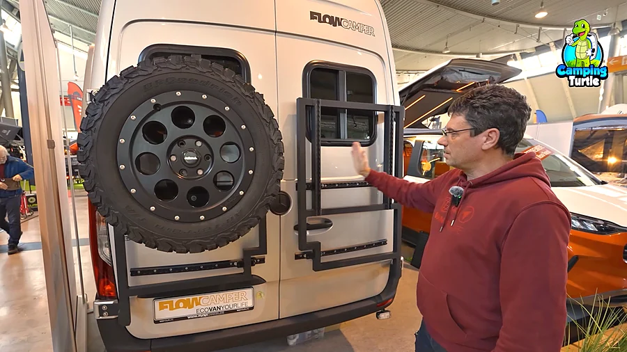 Martin Hemp am Heckträger des Flowcamper MAX mit Reserverad und Airline-Schienen