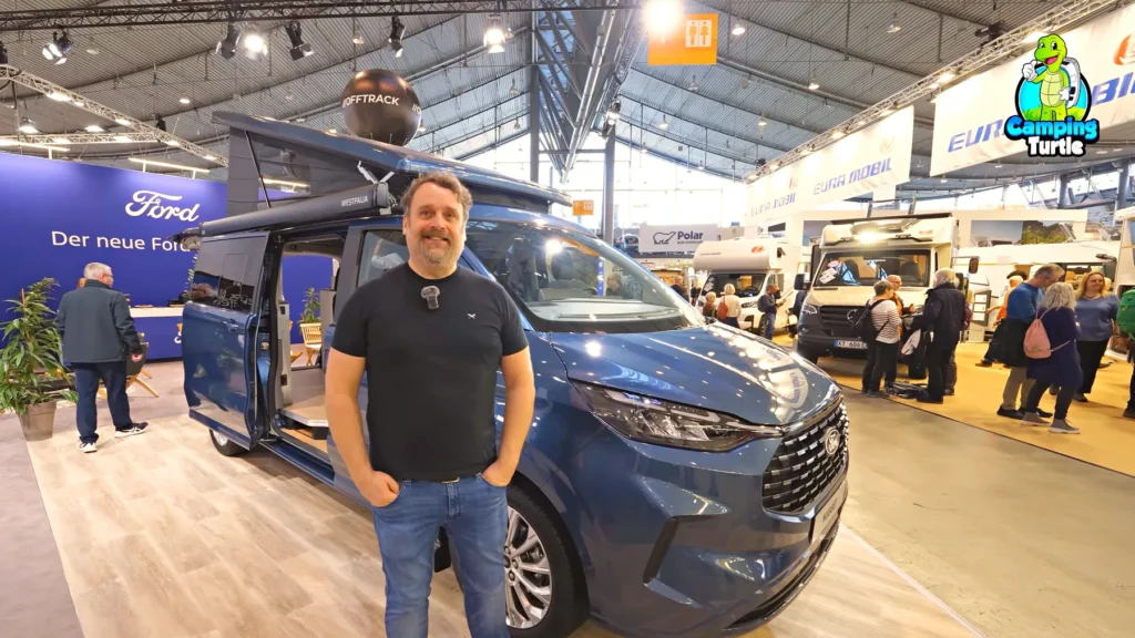 Tiemo Etzold steht auf der CMT 2025 vor dem blauen Ford Nugget L2 mit geöffnetem Aufstelldach und Markise.