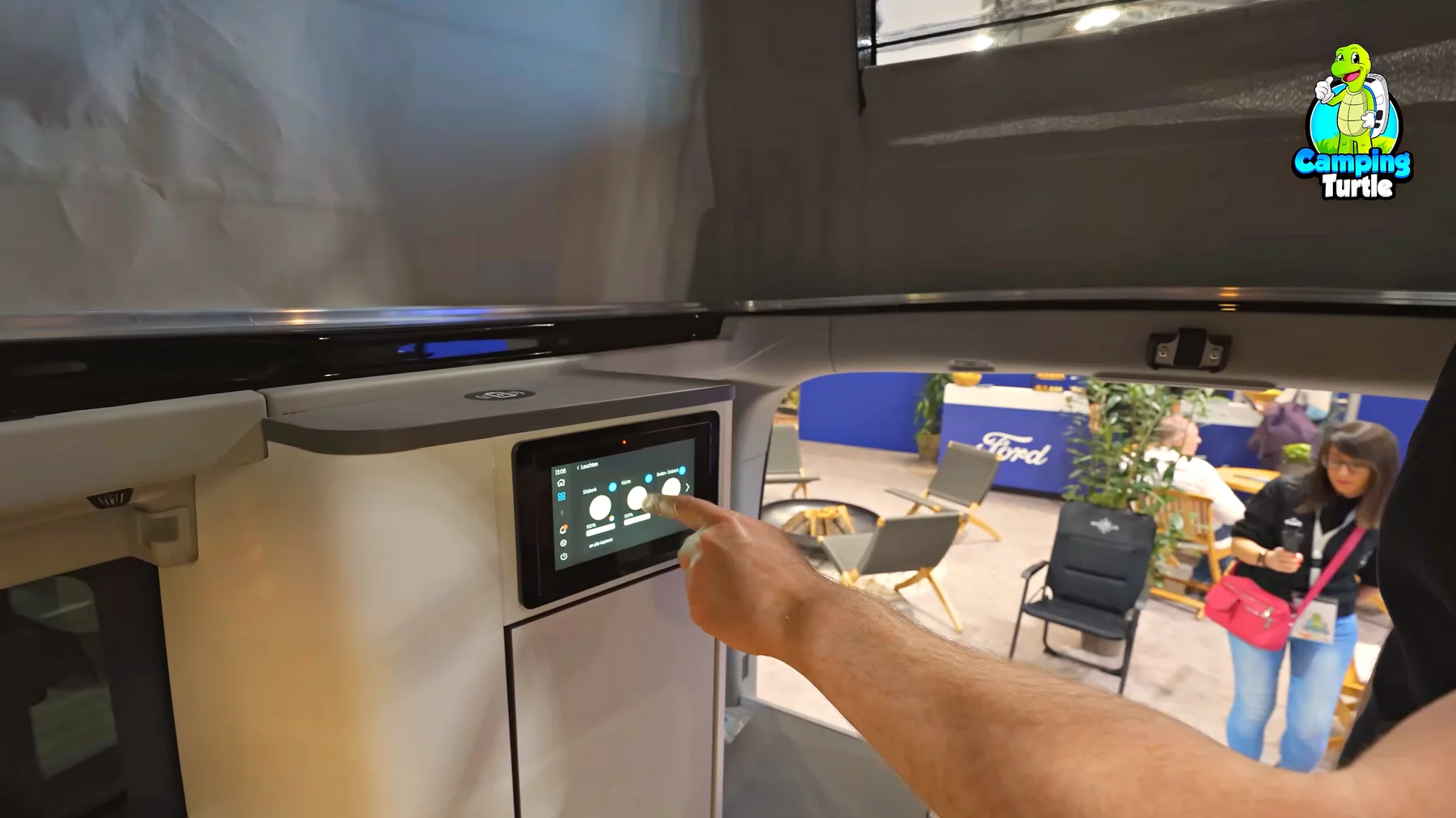 Ein Finger tippt auf den Touchscreen am Schrank, auf dem die Lichtregler zu sehen sind.