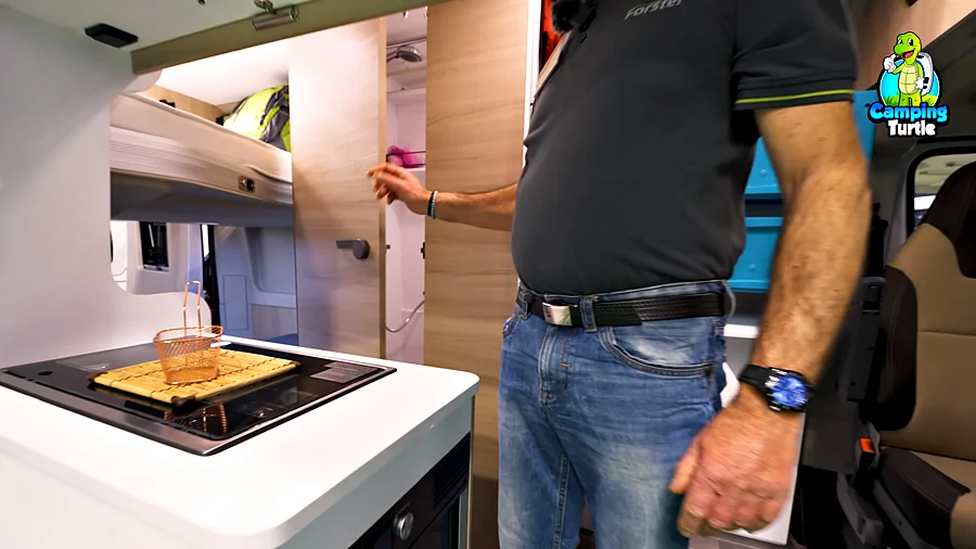 Geöffnete Badtür neben der Küche, dahinter Duschkopf und Staufach