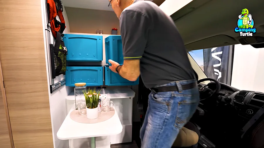 Detlef hängt eine blaue Box an die Wand hinter dem Fahrersitz
