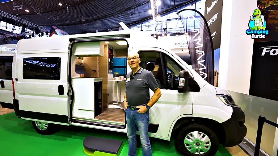 Detlef Bussenius steht vor dem weißen Youngster mit offener Schiebetür auf dem Messestand