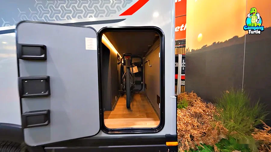 Geöffnete Tür der Heckgarage des Dethleffs Globebus Performance 4x4 T16 mit einem Fahrrad, beleuchtetem Innenraum und Holzboden