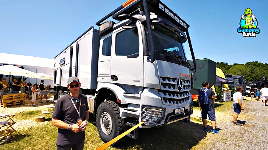 Dirk Wexler steht vor dem grauen Mercedes Arocs mit Wohnkabine auf dem Messegelände
