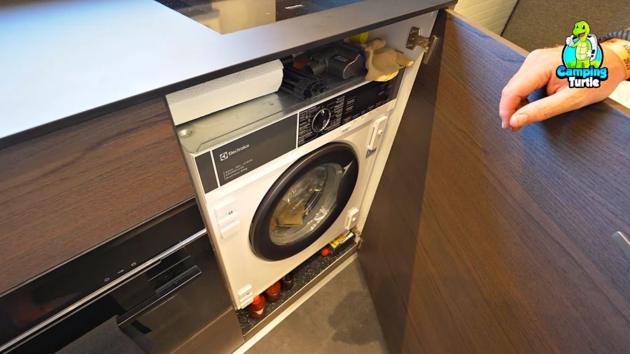 Geöffneter Unterschrank in der Küche mit eingebauter Waschmaschine mit Trockner