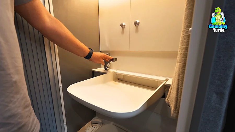 Heruntergeklapptes Waschbecken über der Toilette mit Badschrank