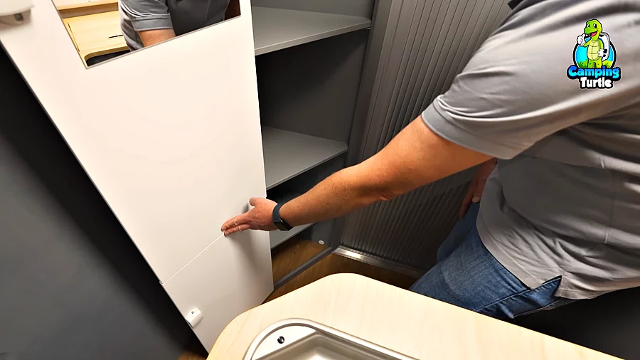 Geöffneter Schrank mit Fachböden neben dem Bad