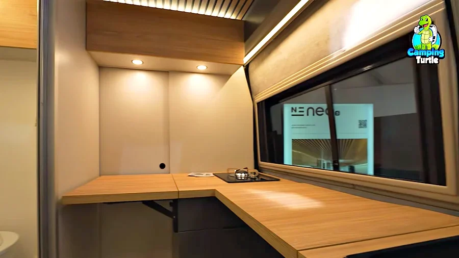L-Küche mit hochgeklappter Arbeitsplatte aus Holz und einem Gaskocher vor der hellen Trennwand