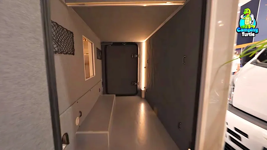Blick in die Heckgarage mit grauer Filzverkleidung, Netzen an der Wand und einer hohen Tür am anderen Ende