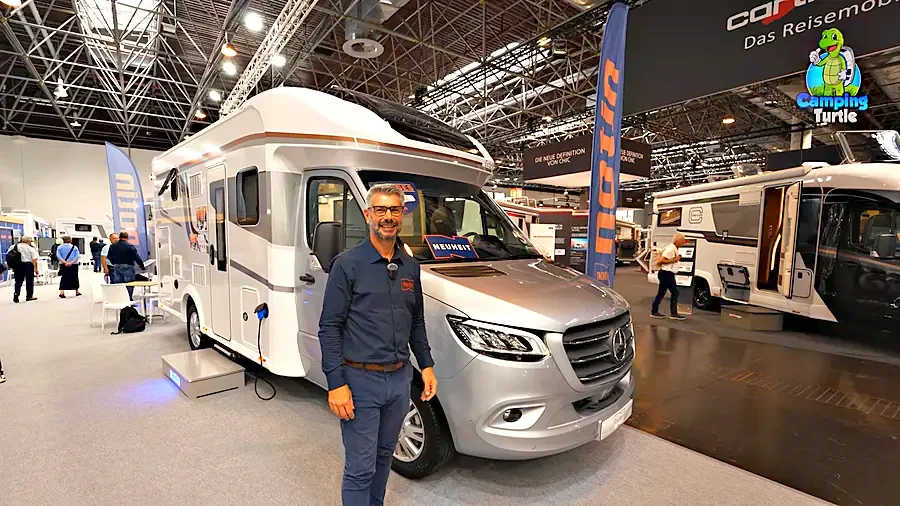 Julien Saura steht vor dem silbernen Notin Bruges auf dem Messestand