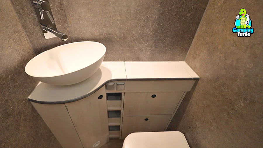 Waschraum mit Aufsatzwaschbecken, Wänden in grauer Betonoptik und einer weißen Toilette