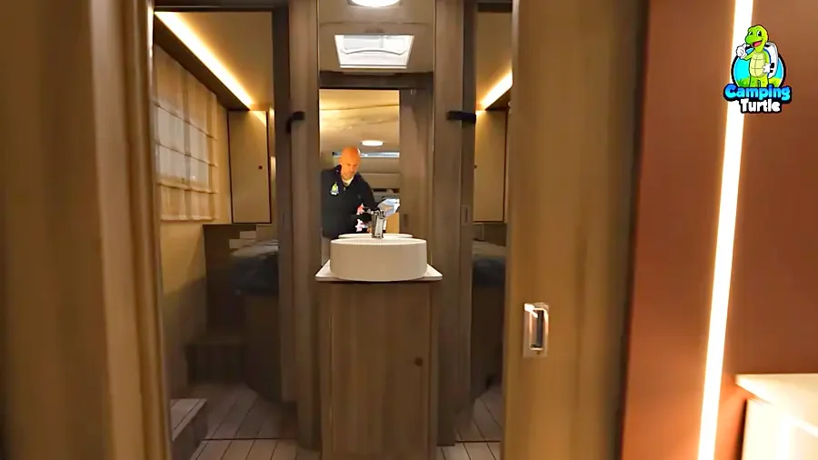 Blick vom Wohnbereich durch das Raumbad des Roller Team Kronos 266 TL, Carlos Funke steht am Waschtisch, dahinter das Schlafzimmer
