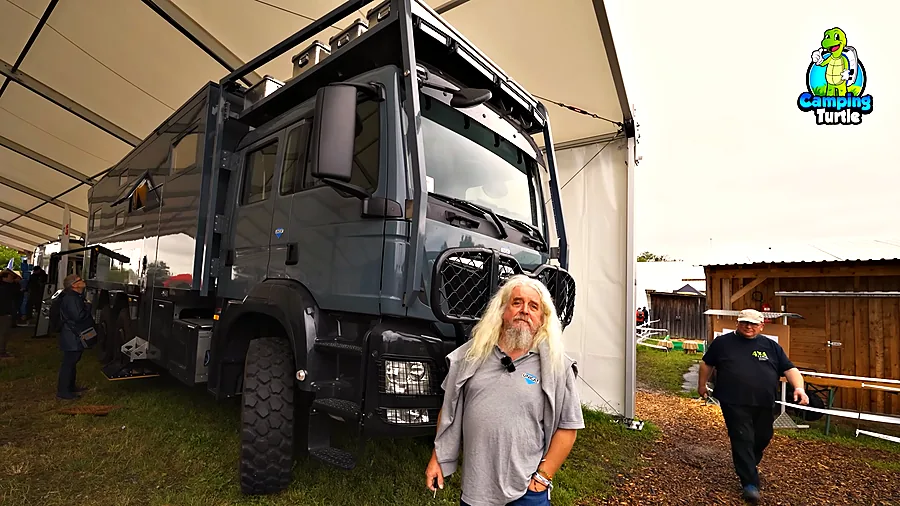 Thomas Waas von UNICAT vor dem MAN TGS 6x6 in einem Messezelt