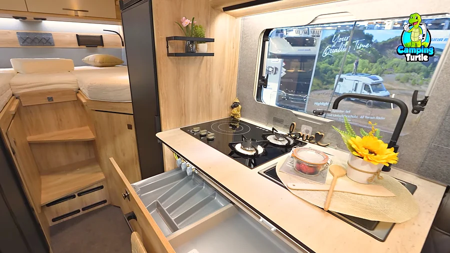 Küche des Eura Mobil Xtura XT 686 EF mit Gas- und Induktionskochfeld, dahinter die Einzelbetten