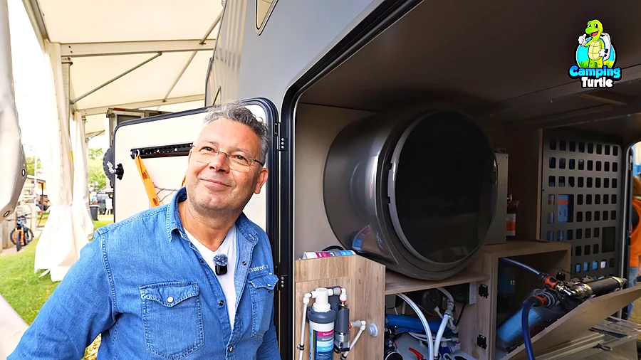 Lupo Neuschl von CARAWATER neben der geöffneten Heckgarage mit Waschmaschine und Wasseraufbereitung